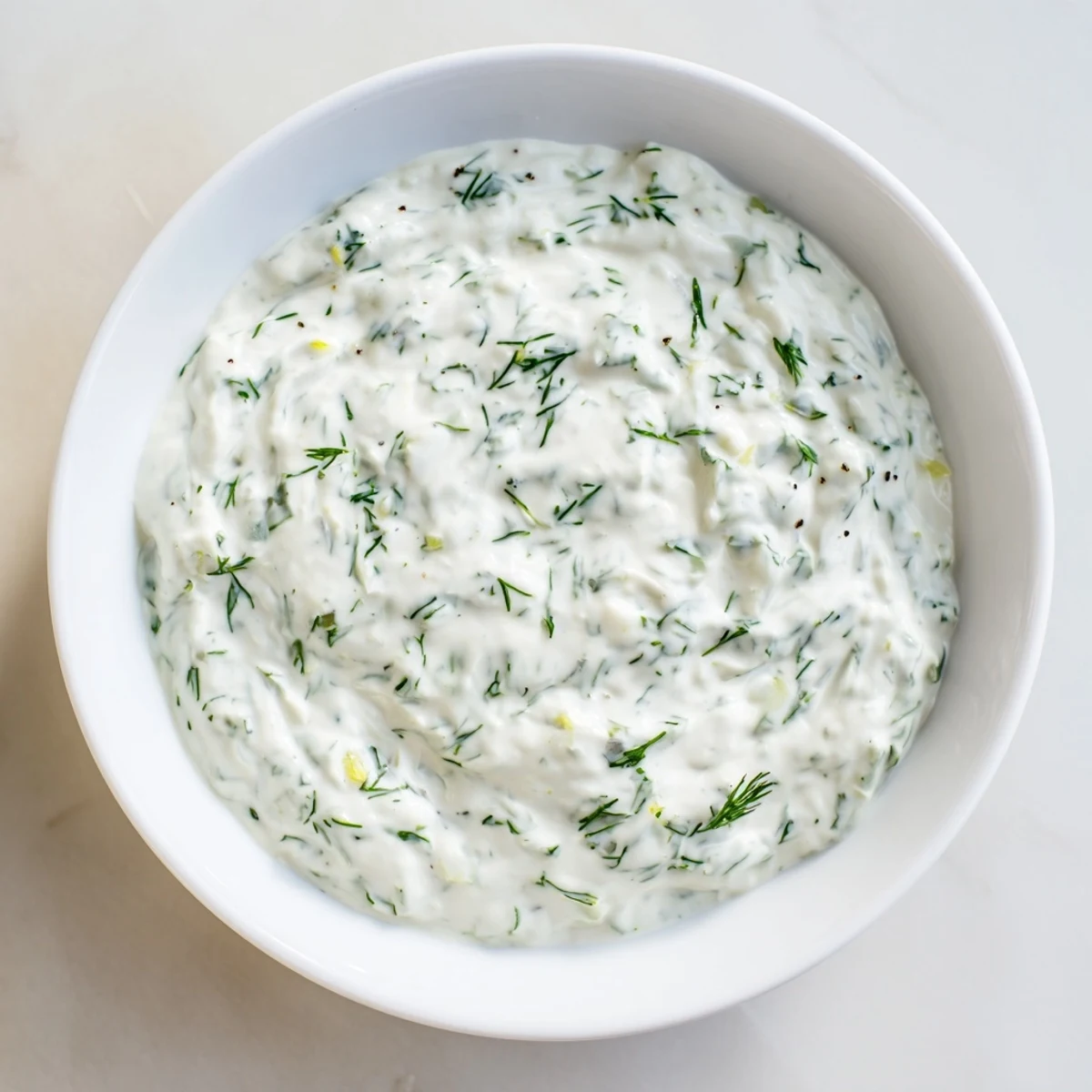 Creamy, tangy Greek Yogurt Herb Dip in a white bowl surrounded by crunchy pita chips, cucumber slices, and vibrant cherry tomatoes.