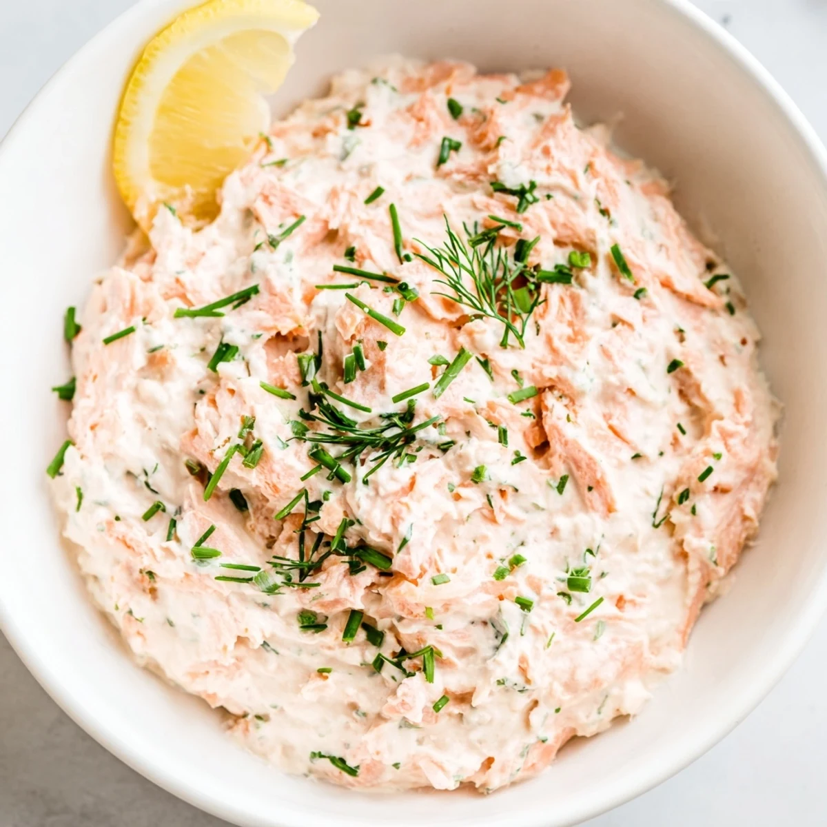 Freshly prepared smoked salmon dip with vibrant chives and a sprinkle of lemon zest, ideal for party platters.