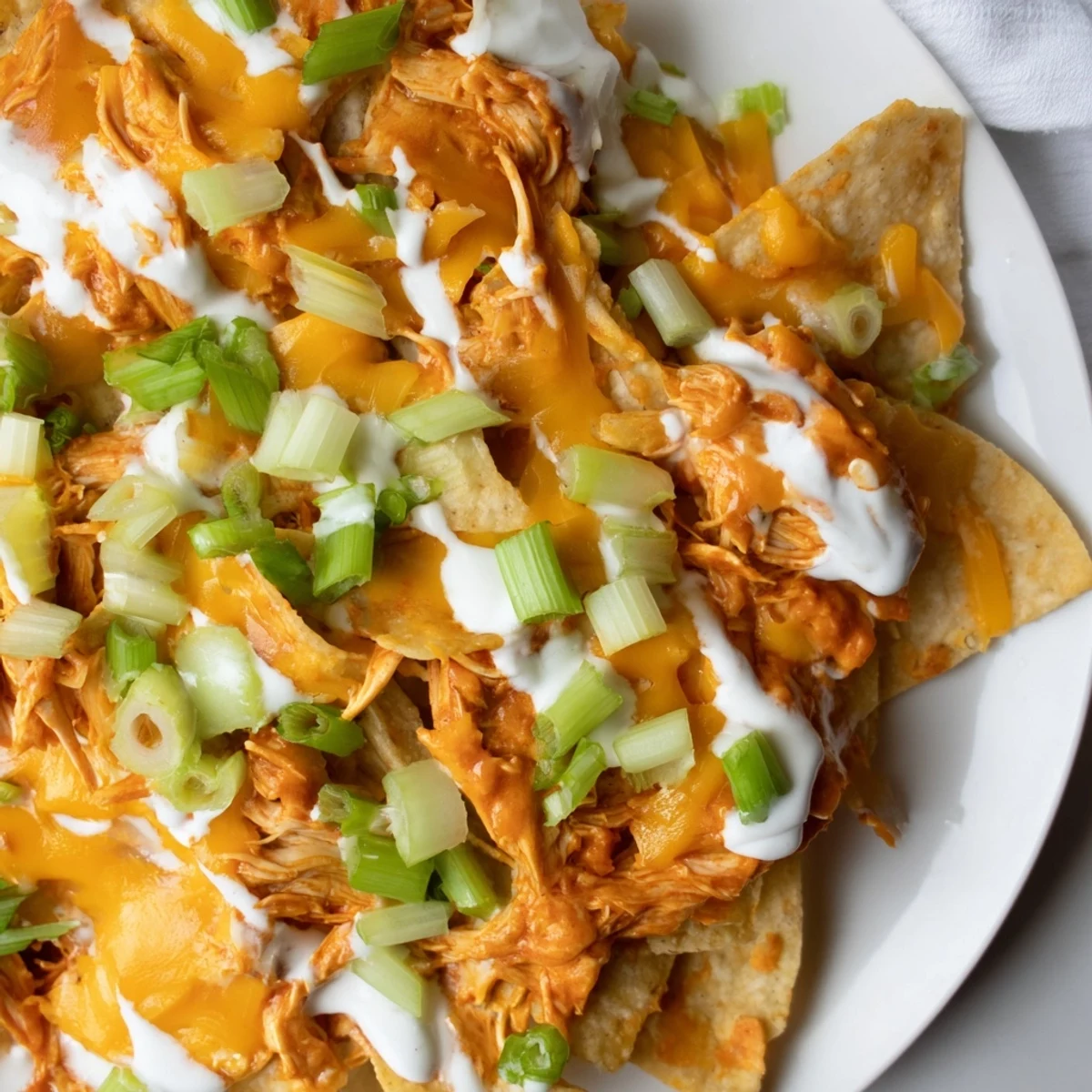 Golden melted cheddar and Monterey Jack cheese over Buffalo chicken nachos with ranch dressing, perfect for casual entertaining.