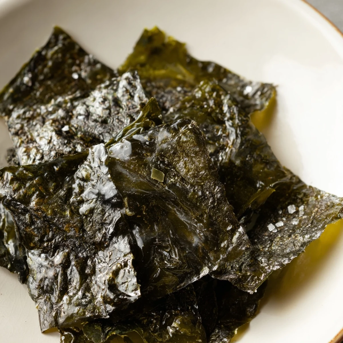 Golden roasted seaweed chips glistening with sesame oil, arranged on a baking sheet after a quick oven roast.  