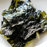 Close-up of crispy, dark green roasted seaweed chips, seasoned with salt and ready to snack.  