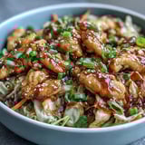 Steaming savory Egg Roll Bowls with Chicken and Cabbage made with golden chicken, shredded carrots, and green cabbage in a tangy soy sauce.