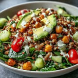 Hearty Ancient Grains Bowl with farro and quinoa, topped with avocado and lemon tahini dressing.