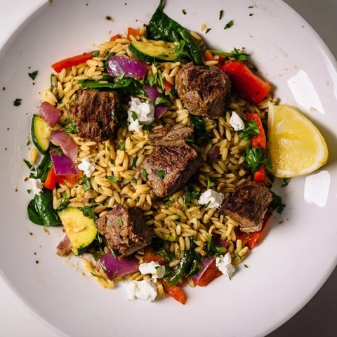 Steaming Smoky Mediterranean Lamb and Orzo Supper, garnished with feta and fresh parsley, enticing flavors.