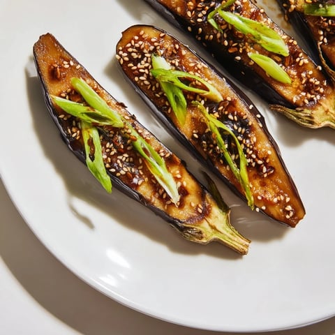 Freshly broiled miso glazed eggplant halves glistening with caramelized sauce and topped with sesame seeds and green onions.  