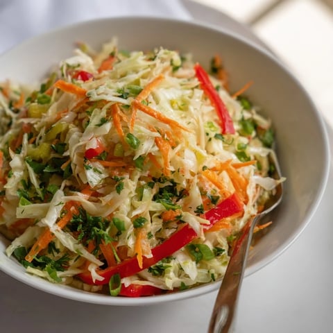Bright and crisp Sauerkraut Slaw with shredded green cabbage and grated carrots in a ceramic bowl.