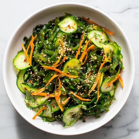 Bright green wakame seaweed salad with crisp cucumber ribbons and julienned carrot tossed in a glossy sesame-ginger dressing.