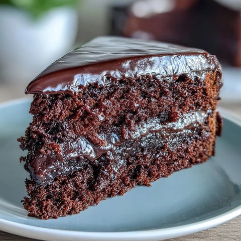 Freshly baked Easy Chocolate Fudge Cake layers on a wire rack, showcasing moist crumbs and a rich, glossy chocolate icing being smoothed on.