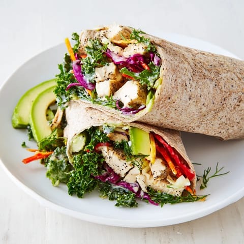 Close-up of a Poppy-Inspired Chicken Salad Wrap, featuring colorful ingredients rolled in a whole wheat tortilla.