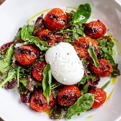 A close-up view of the Charred Tomato Salad with Burrata, showcasing fresh basil and balsamic drizzle.