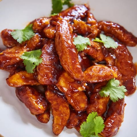 A close-up of a honey sriracha chicken wrap, sliced to reveal juicy glazed chicken, crunchy red bell peppers, and fresh cilantro tucked inside a warm tortilla.