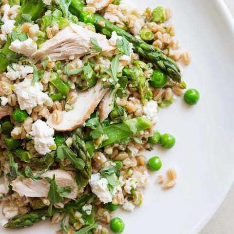A close-up of warm farro chicken salad topped with crumbled feta and fresh herbs, perfect for an easy, healthy weeknight dinner.