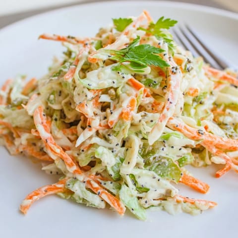 A bowl of Green Cabbage and Apple Slaw with fresh parsley and poppy seeds, perfect for a summer picnic or BBQ side.  