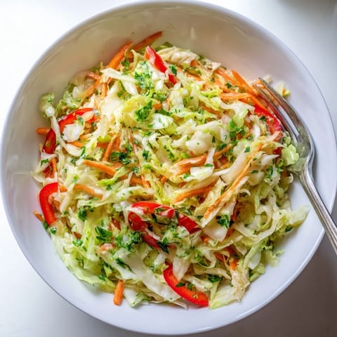 A vibrant green Sauerkraut Slaw featuring red bell pepper slices and fresh parsley, ready to serve.