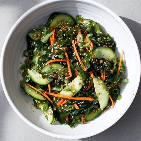 A refreshing Japanese seaweed salad garnished with toasted sesame seeds and fresh cilantro, served in a white ceramic bowl.