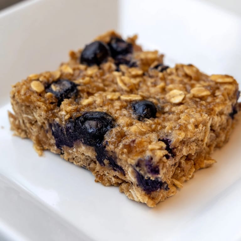 Fresh blueberries dot the top of these soft, chewy blueberry banana oatmeal protein bars, a delicious treat.