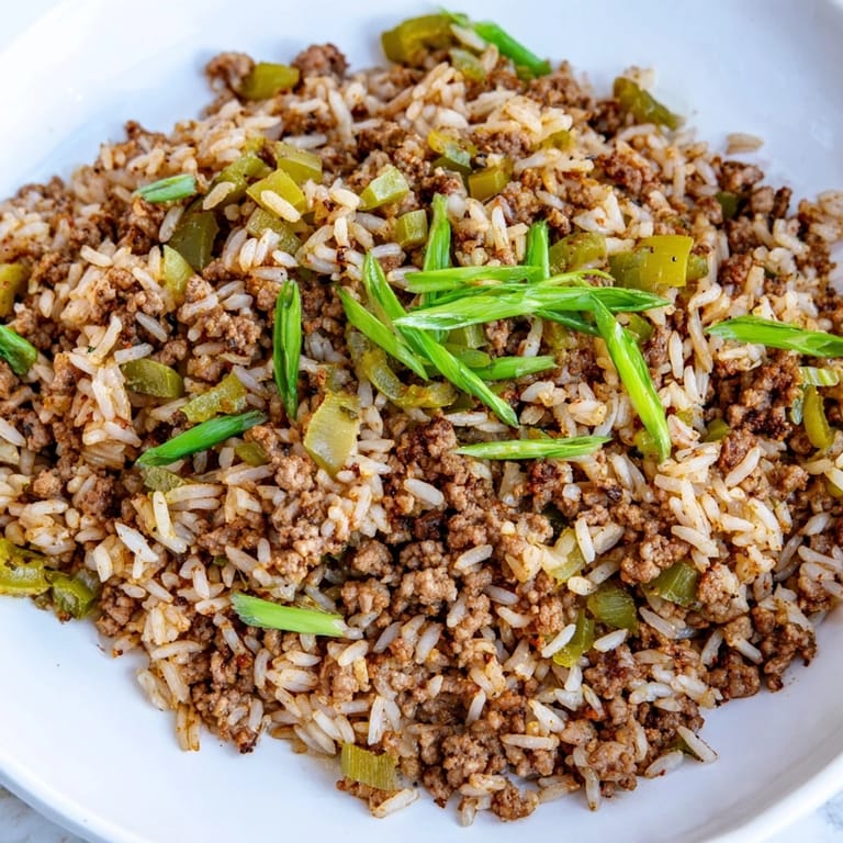 Golden-brown Cajun Dirty Rice, garnished with green onions, ready to be served and enjoyed.