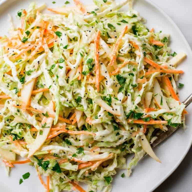 Vibrant green cabbage and tart apple slaw, lightly dressed with a creamy Dijon vinaigrette, garnished for a refreshing crunch.