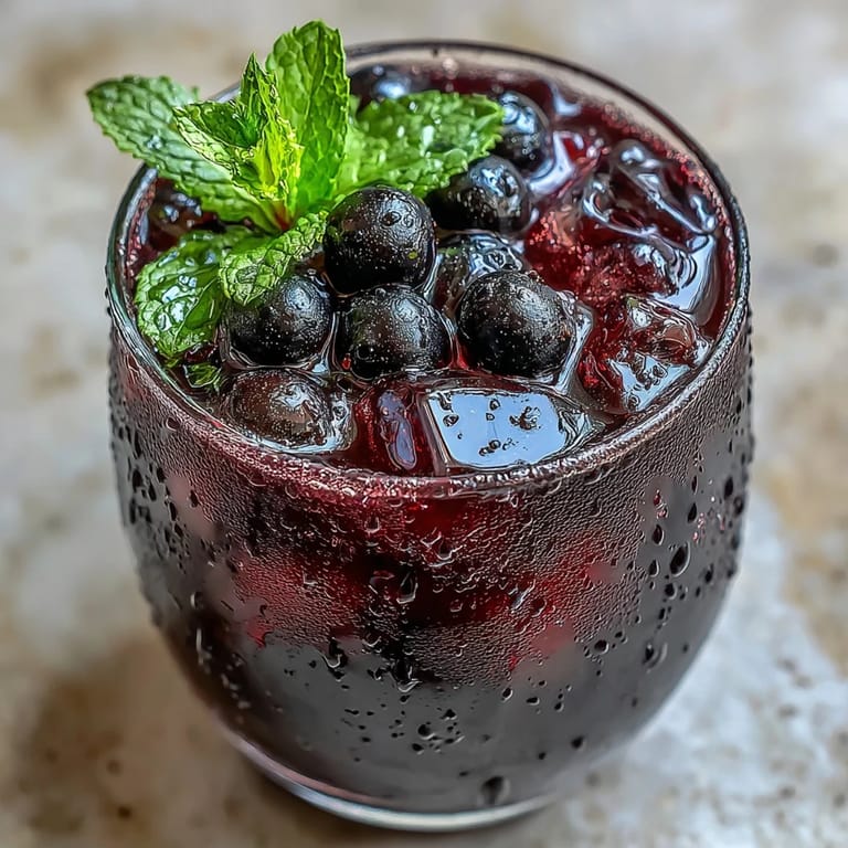 Refreshing Black Currant It Berry Celebration Drink infused water showcases lemon slices and crushed berries in a clear pitcher.