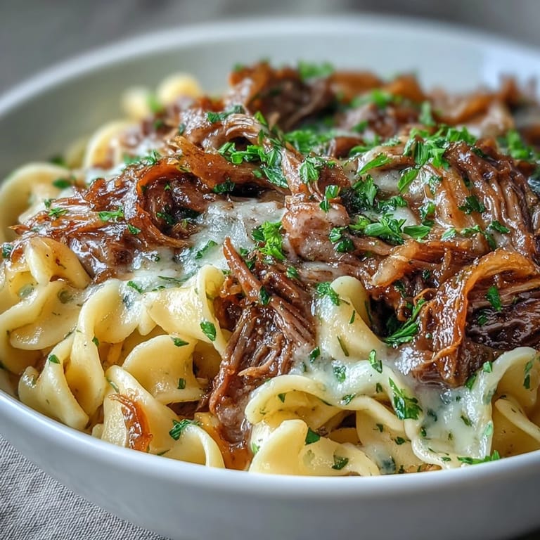 Hearty Crockpot French Onion Pot Roast Pasta with fresh parsley garnish on a rustic plate.