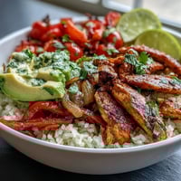 Skinny Chicken Fajita Meal Prep Bowls with Cilantro-Lime Rice in glass containers with avocado slices and cherry tomatoes.