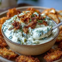 Creamy fried pickle dip with crispy garnishes, ready for dipping.